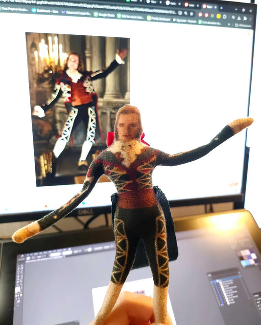Harlequin Lestat figure displayed in front of a computer monitor against an image of actor Sam Reid in character.